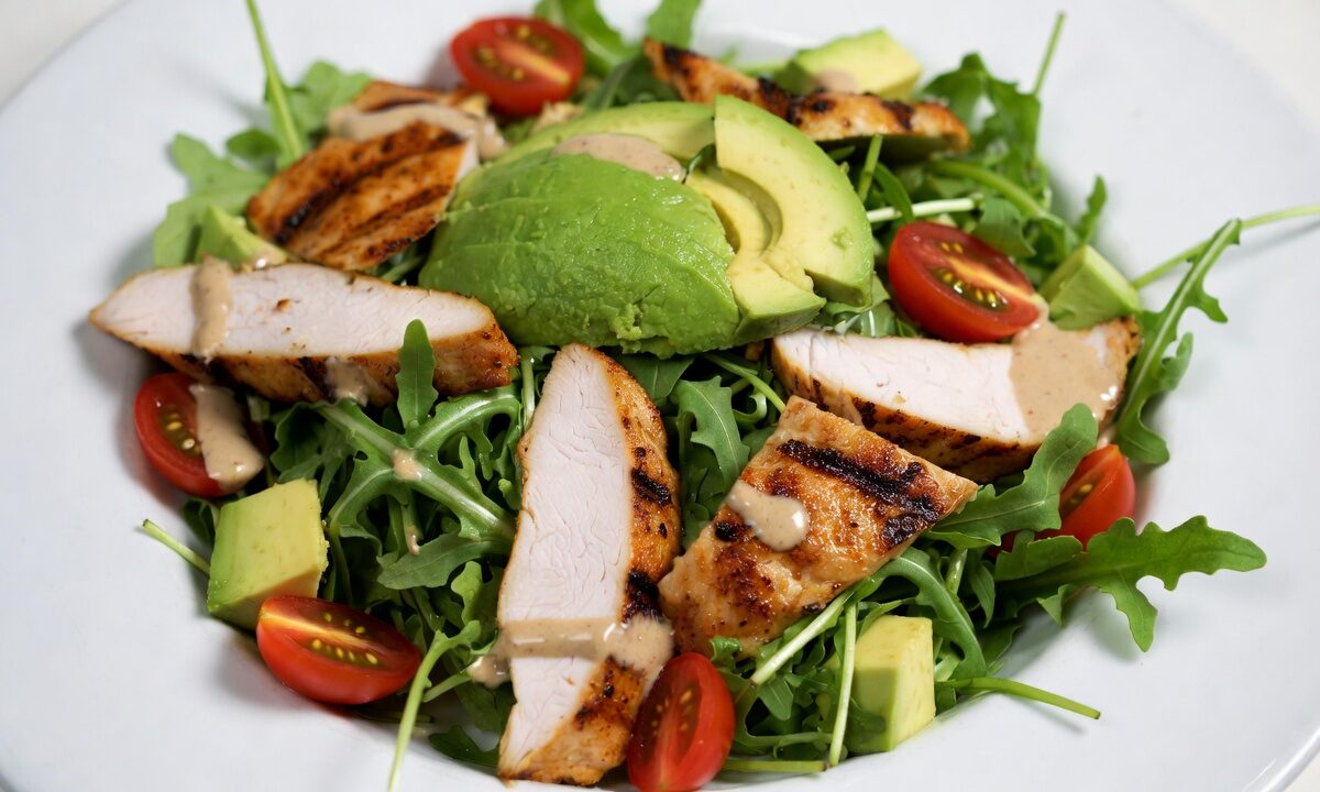 سلطة دجاج شرق أوسطية كيتو مع دجاج مشوي، أفوكادو طازج، جرجير، طماطم، وصلصة طحينية مدخنة، مثالية للوجبات المنخفضة الكارب.