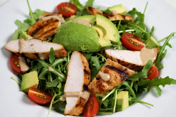 سلطة دجاج شرق أوسطية كيتو مع دجاج مشوي، أفوكادو طازج، جرجير، طماطم، وصلصة طحينية مدخنة، مثالية للوجبات المنخفضة الكارب.